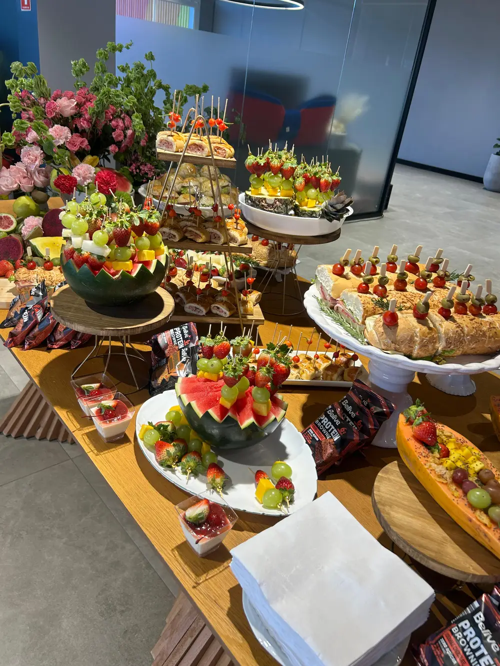 Mesa de coffee break corporativo com frutas, salgados e doces